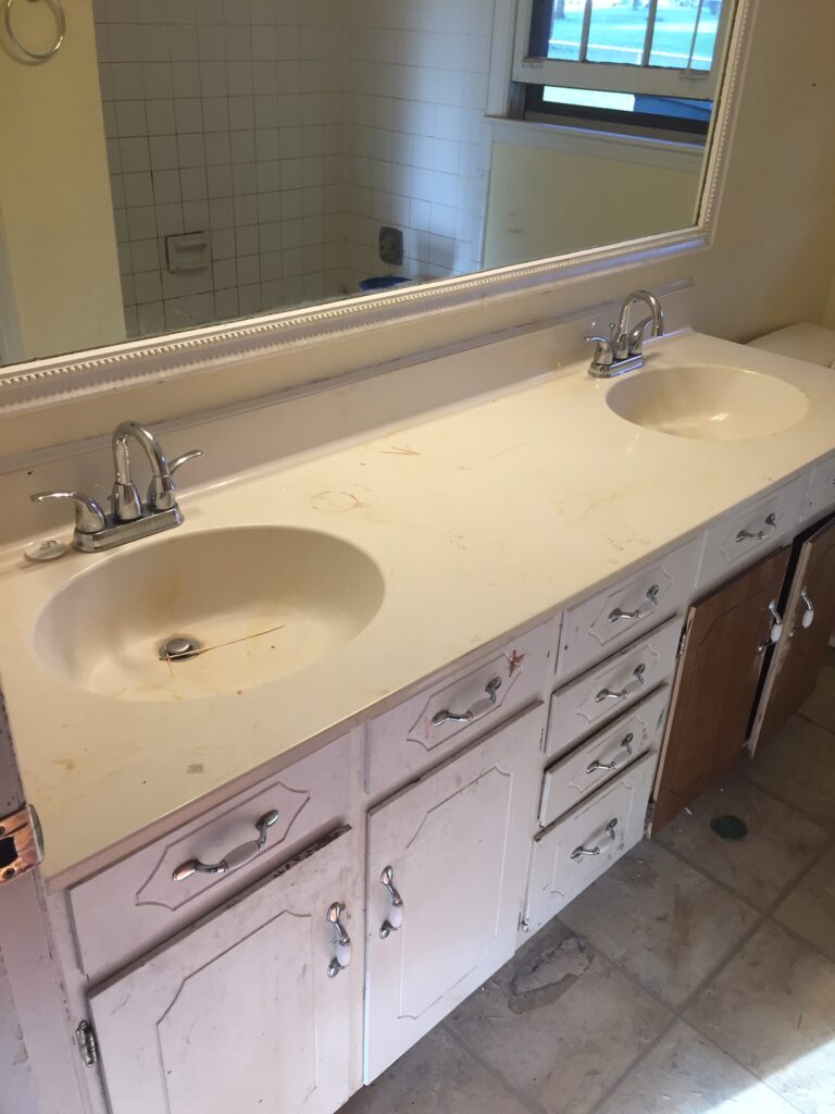 Cultured marble double-sink vanity top exhibiting stains, peeling and looking worn-out.(Cabinetry was also in need of a refinish) (BEFORE)